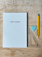 Load image into Gallery viewer, Diary planner, yellow pen, and ruler on a wooden surface
